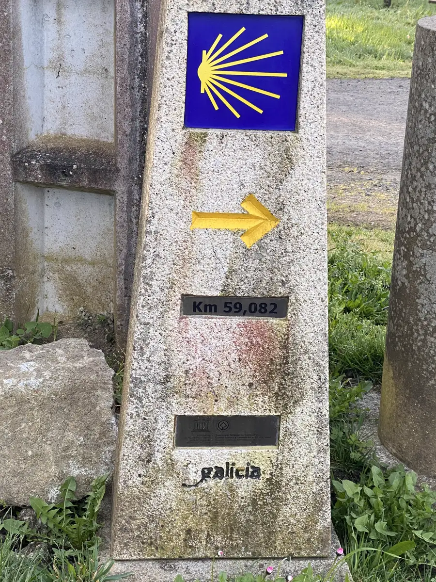 A stone Camino waymarker with a yellow arrow